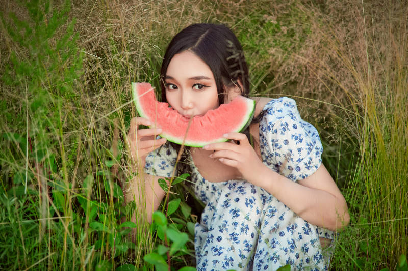 夏天在公园湖边开心吃西瓜的美女