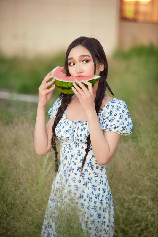 夏天在公园湖边开心吃西瓜的美女