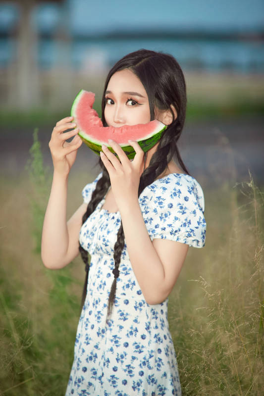 夏天在公园湖边开心吃西瓜的美女
