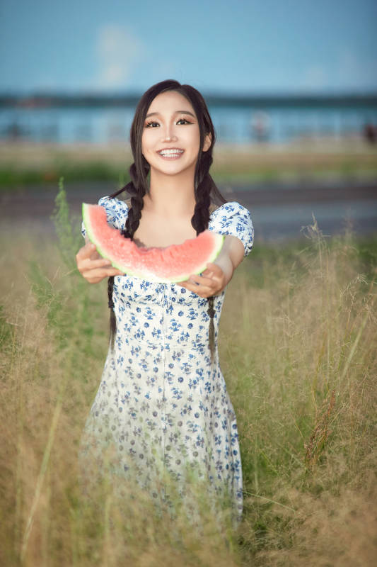 夏天在公园湖边开心吃西瓜的美女