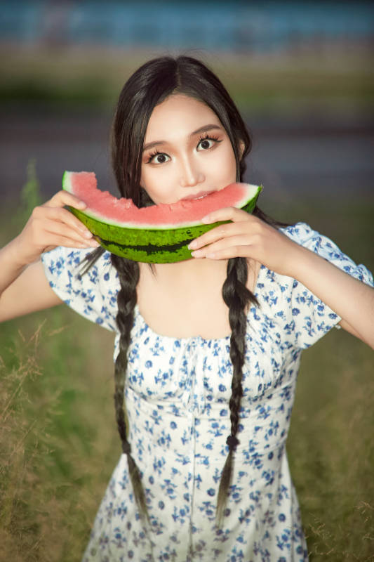 夏天在公园湖边开心吃西瓜的美女