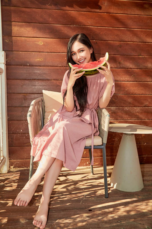 夏天在木质别墅门廊外吃西瓜的美女