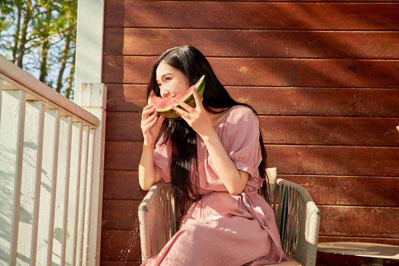 夏天在木质别墅门廊外吃西瓜的美女