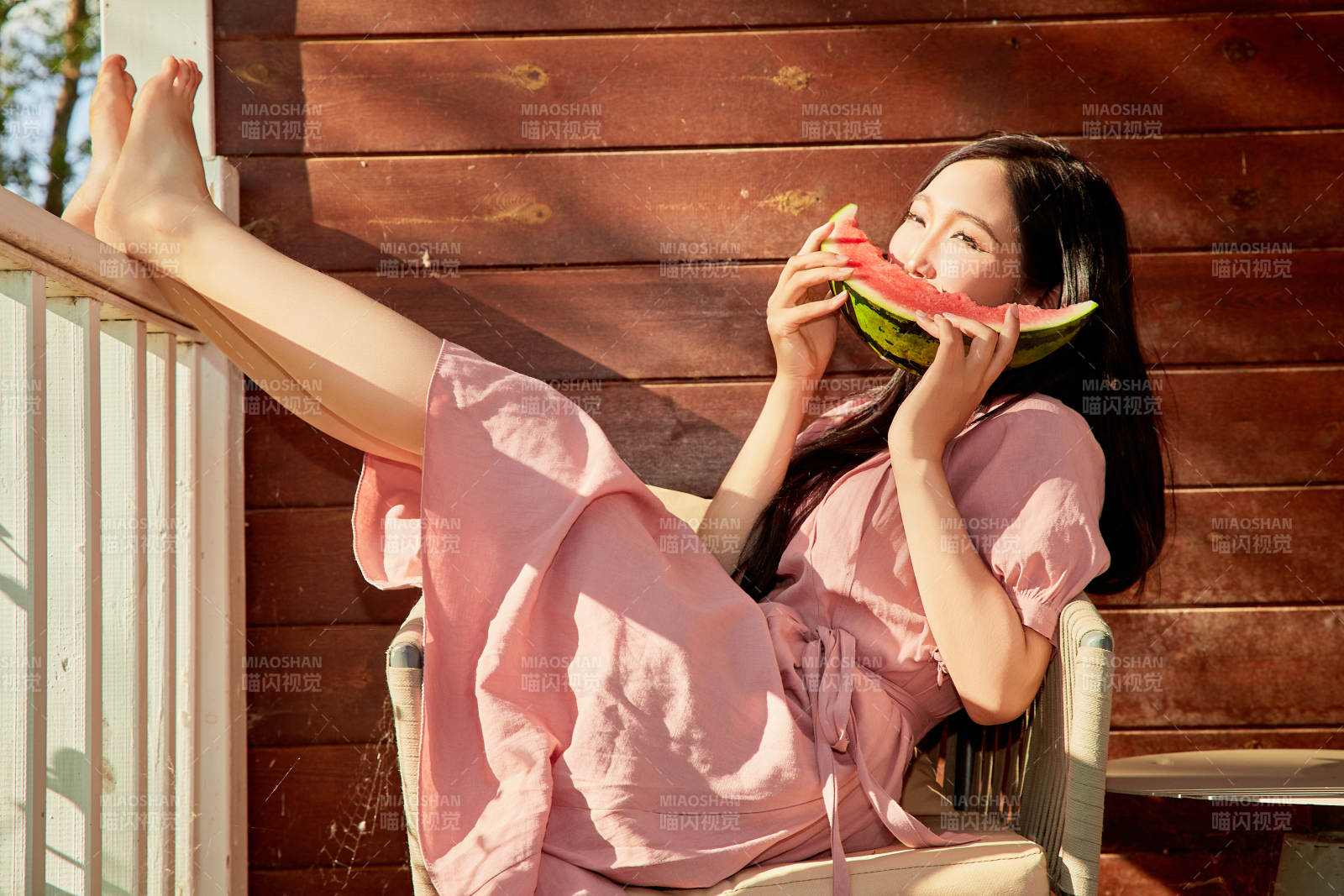 夏天在木質別墅門廊外吃西瓜的美女