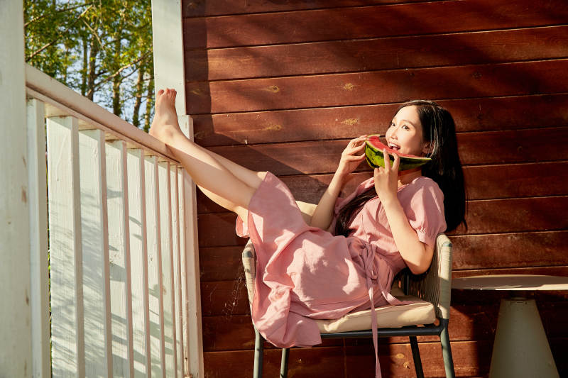 夏天在木质别墅门廊外吃西瓜的美女