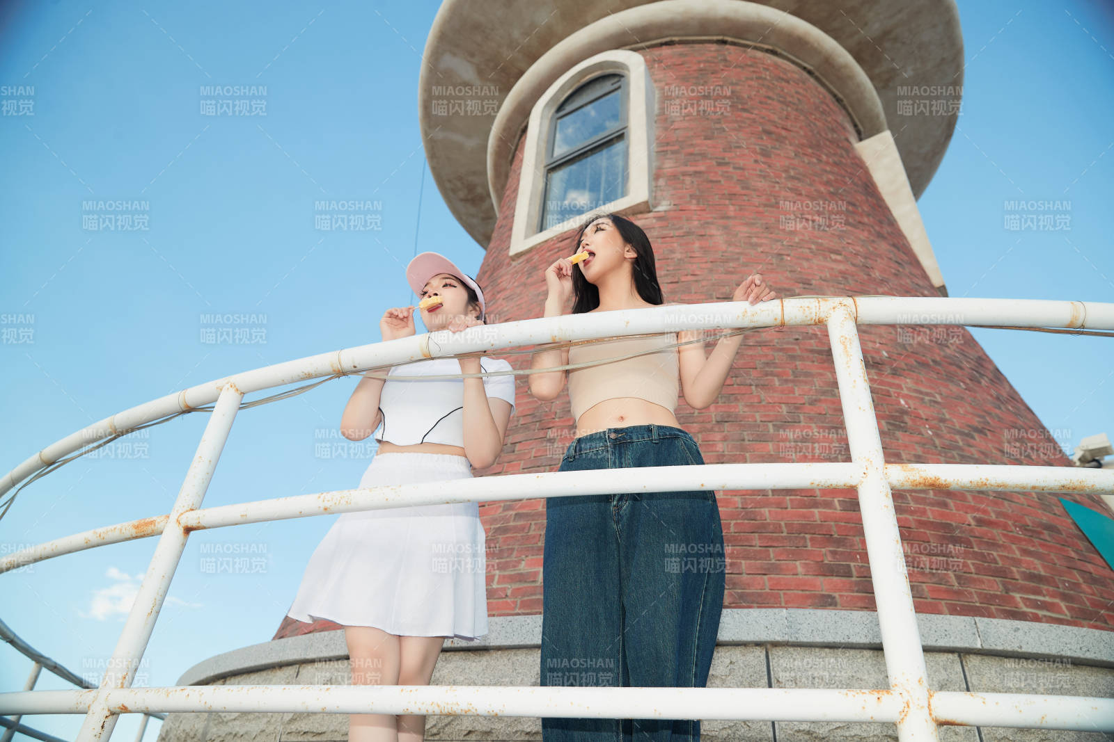 盛夏在景區湖邊燈塔上拍照游玩的美女們