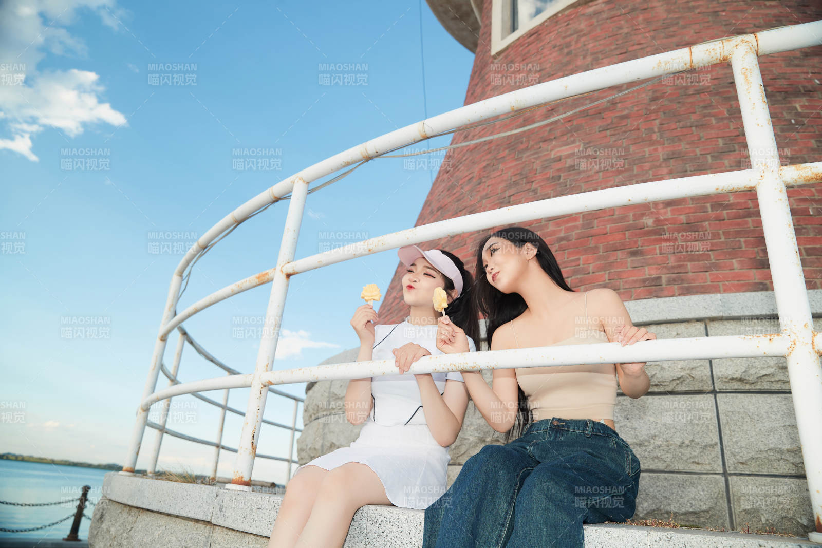 盛夏在景區湖邊燈塔上拍照游玩的美女們