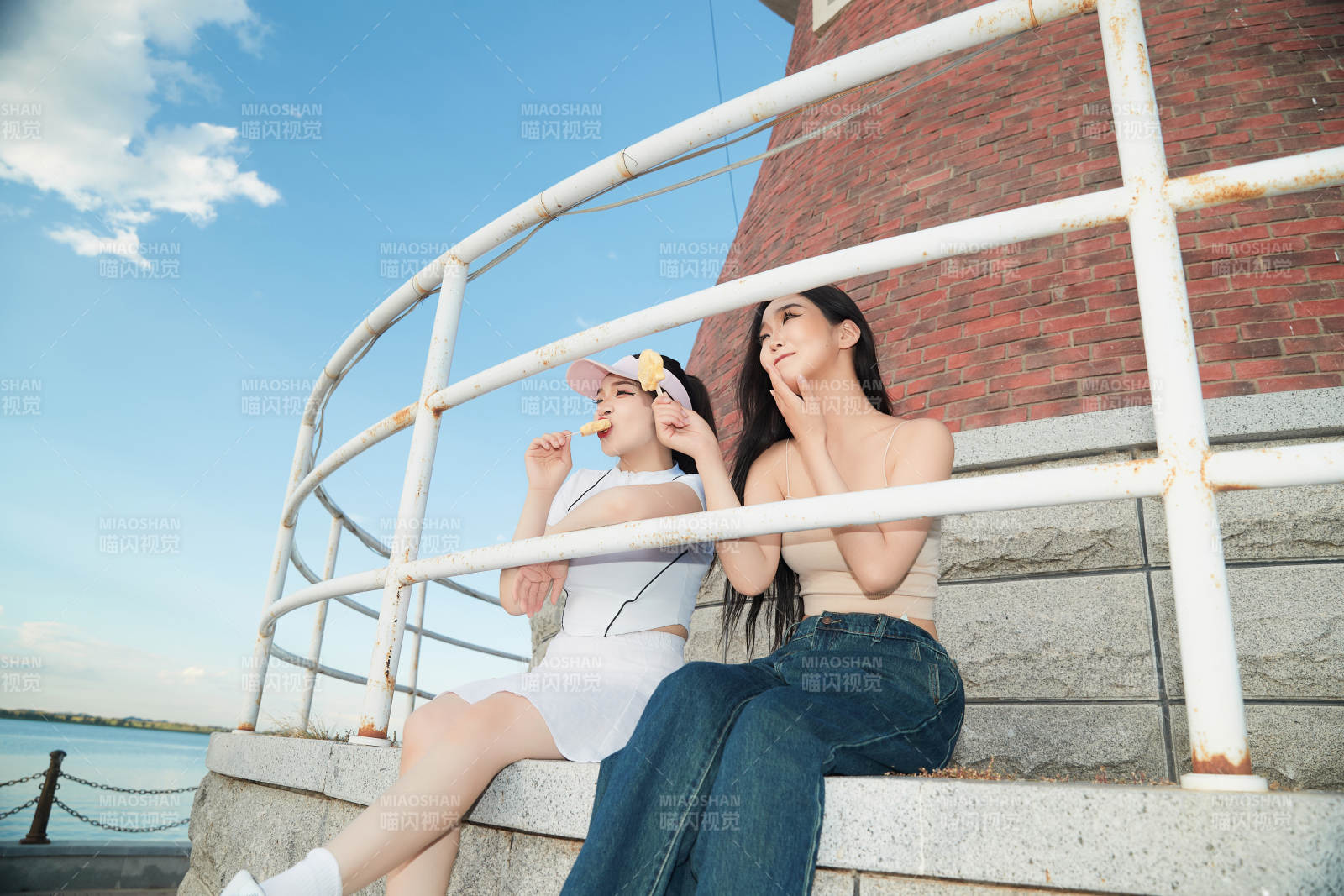 盛夏在景區(qū)湖邊燈塔上拍照游玩的美女們