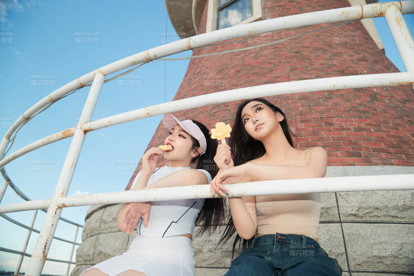 盛夏在景区湖边灯塔上拍照游玩的美女们