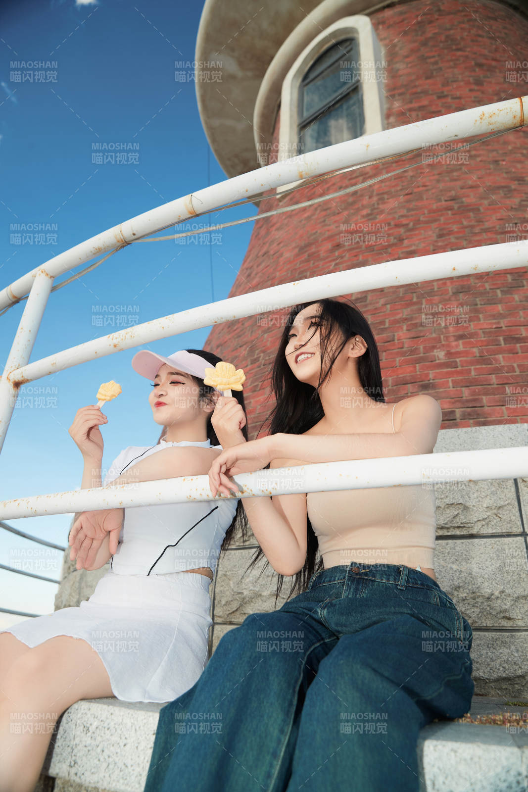 盛夏在景區(qū)湖邊燈塔上拍照游玩的美女們