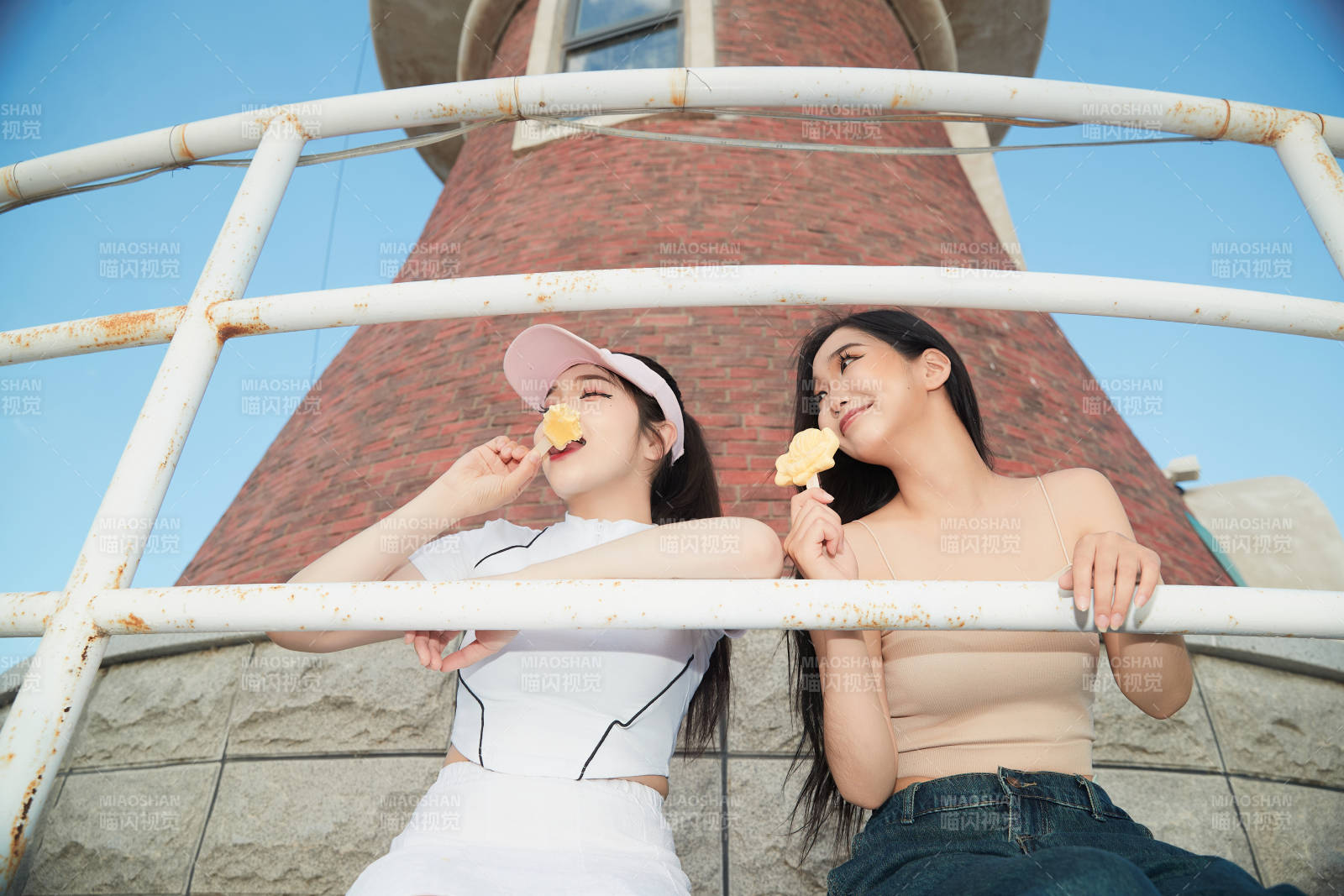 盛夏在景區(qū)湖邊燈塔上拍照游玩的美女們