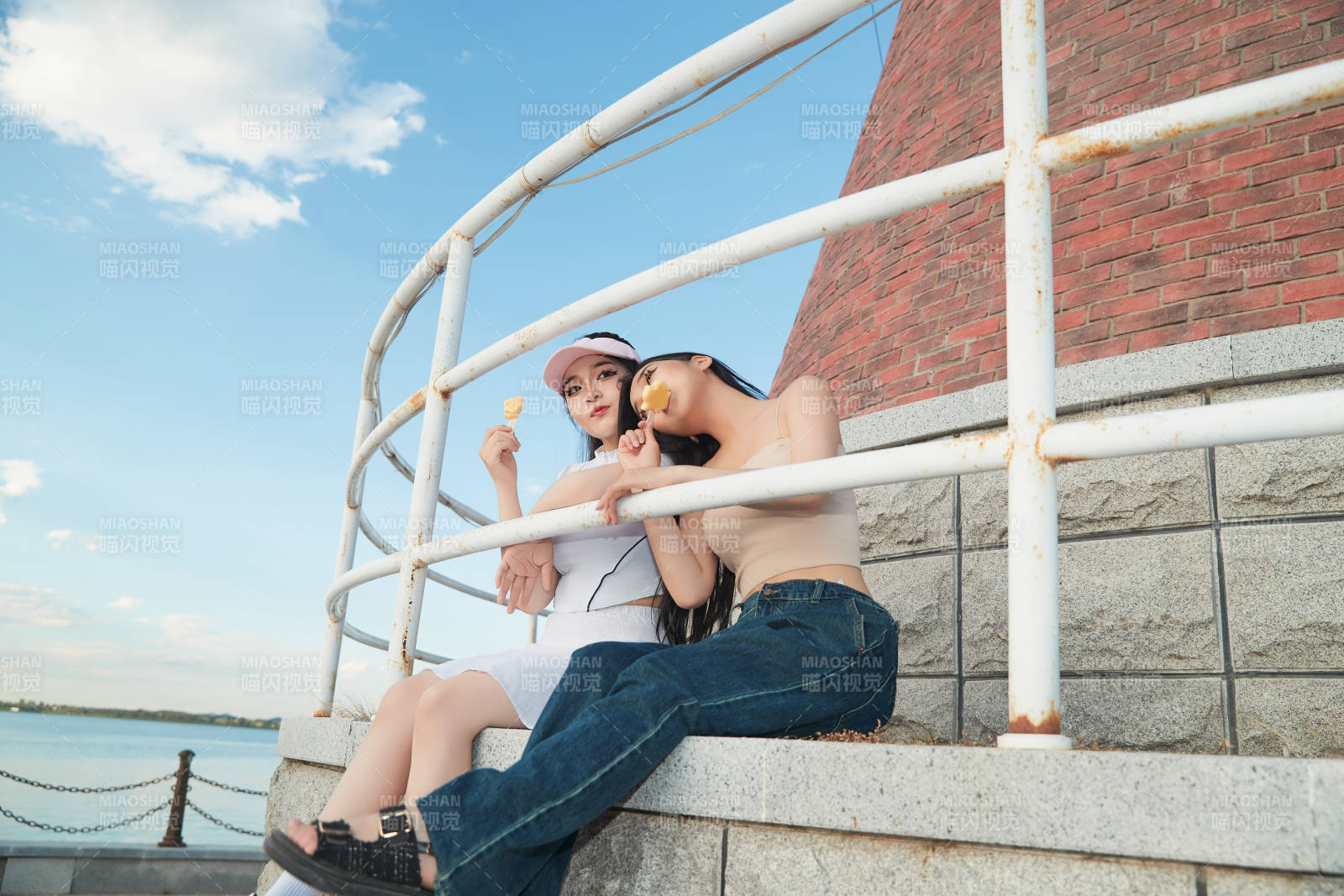 盛夏在景區湖邊燈塔上拍照游玩的美女們