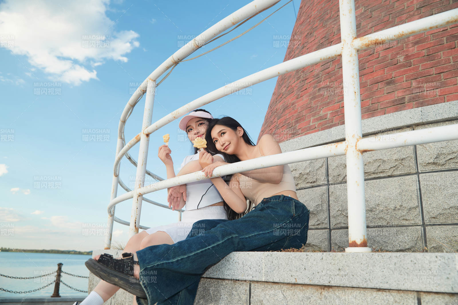 盛夏在景區湖邊燈塔上拍照游玩的美女們