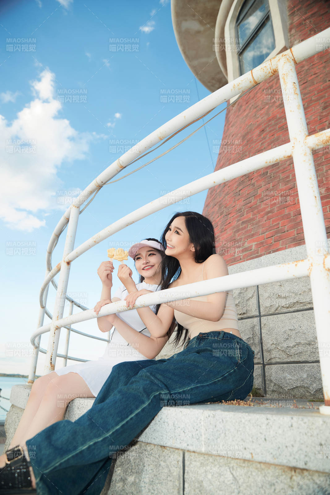 盛夏在景區湖邊燈塔上拍照游玩的美女們