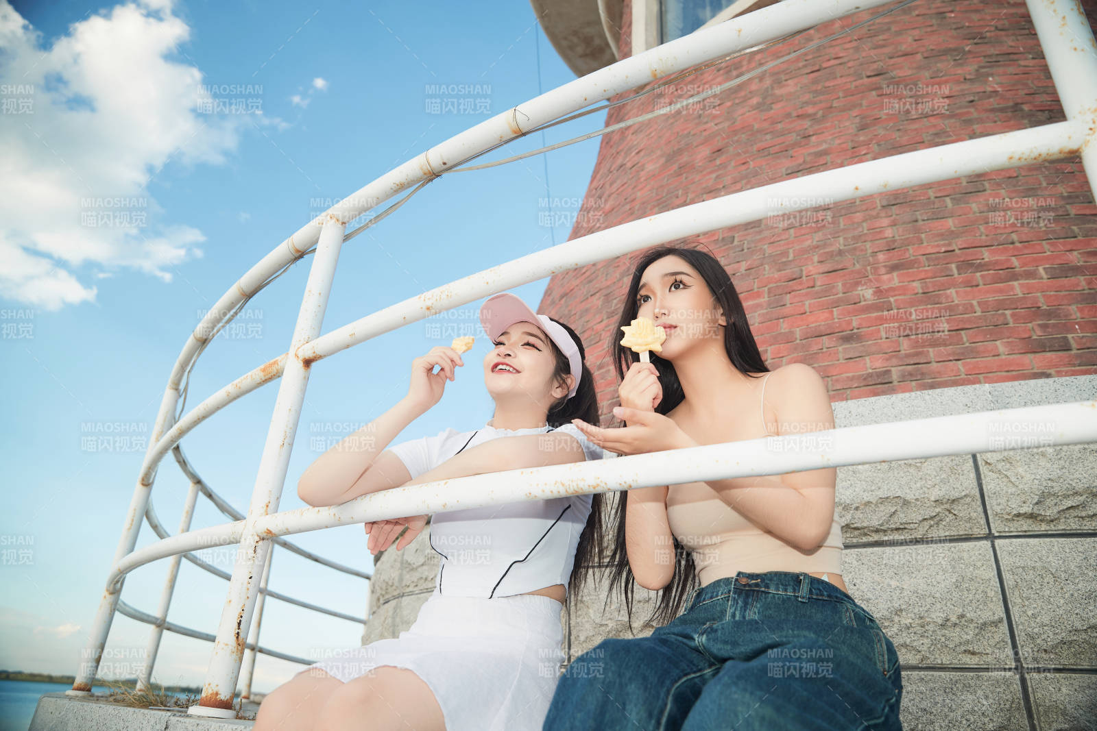 盛夏在景區湖邊燈塔上拍照游玩的美女們