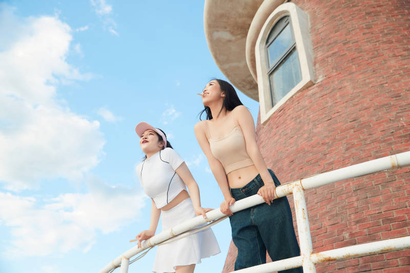 盛夏在景区湖边灯塔上拍照游玩的美女们