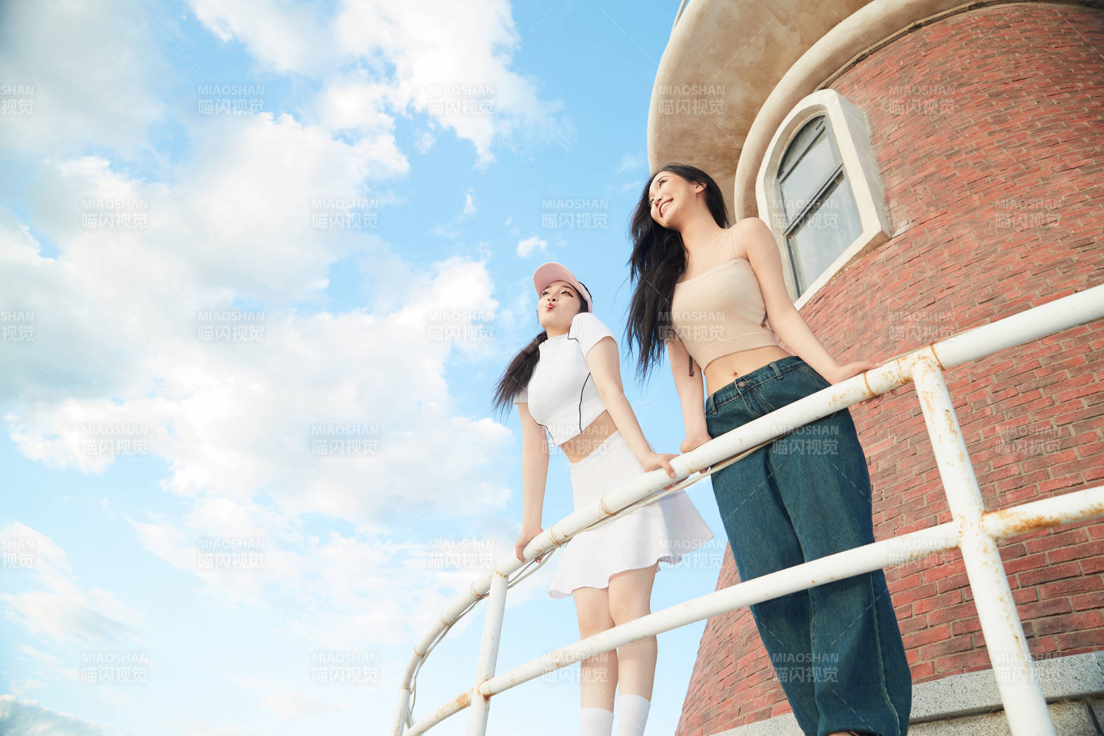 盛夏在景區湖邊燈塔上拍照游玩的美女們