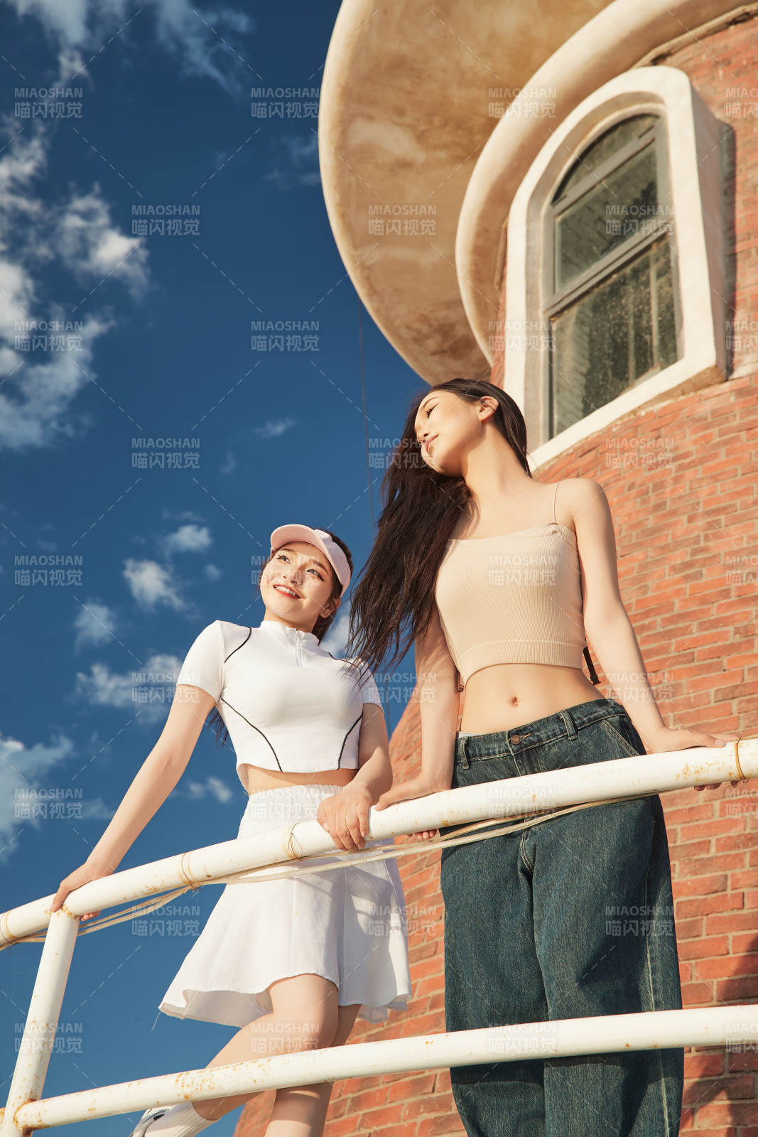 盛夏在景區湖邊燈塔上拍照游玩的美女們