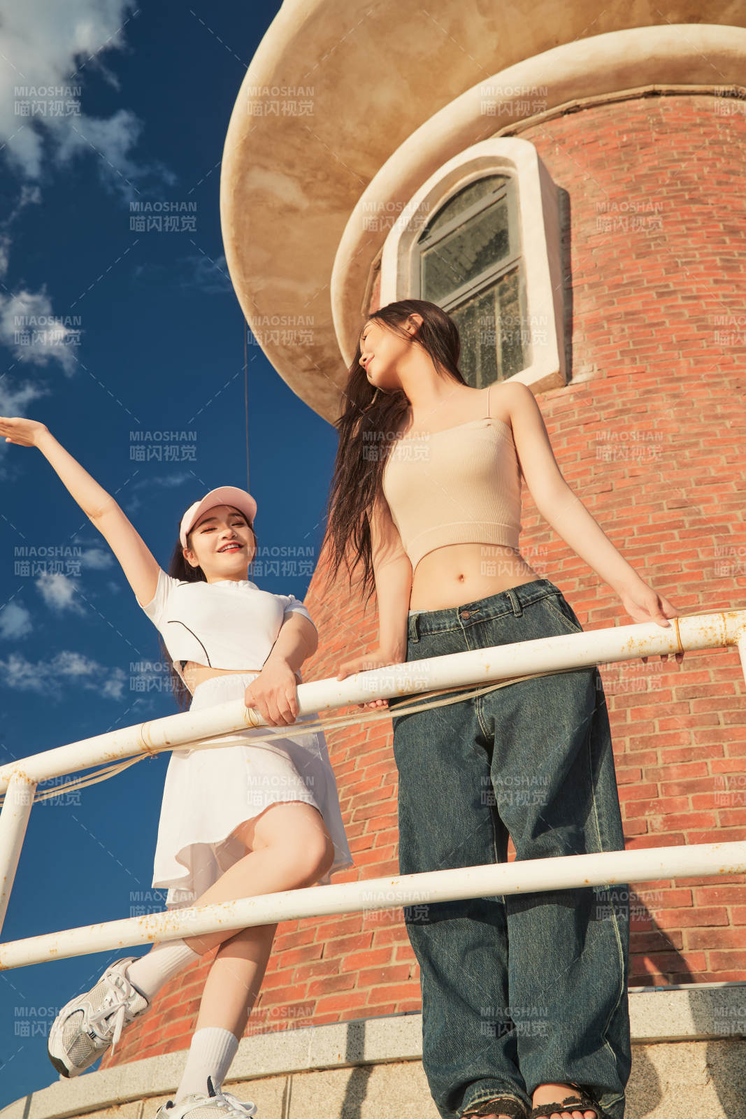 盛夏在景區湖邊燈塔上拍照游玩的美女們