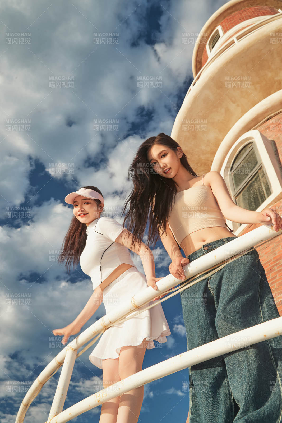 盛夏在景區湖邊燈塔上拍照游玩的美女們