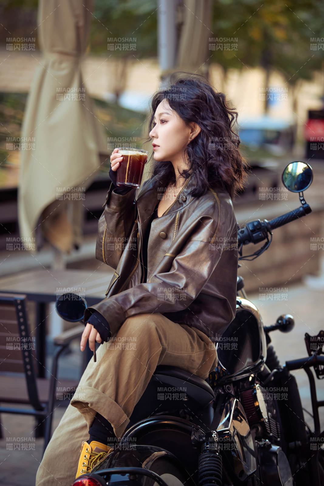 手拿冰美式咖啡坐在摩托上的亞洲美女