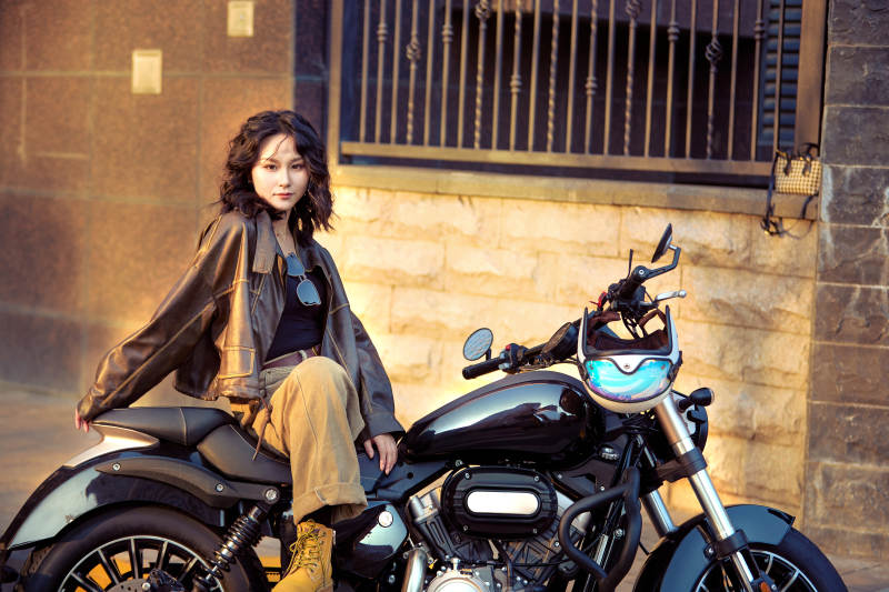 夕阳午后骑复古摩托进行拍照的东方美女