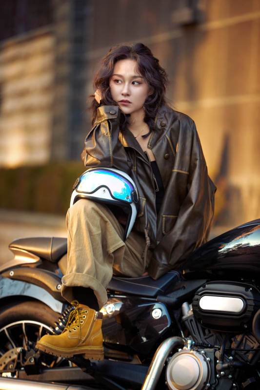 夕阳午后骑复古摩托进行拍照的东方美女