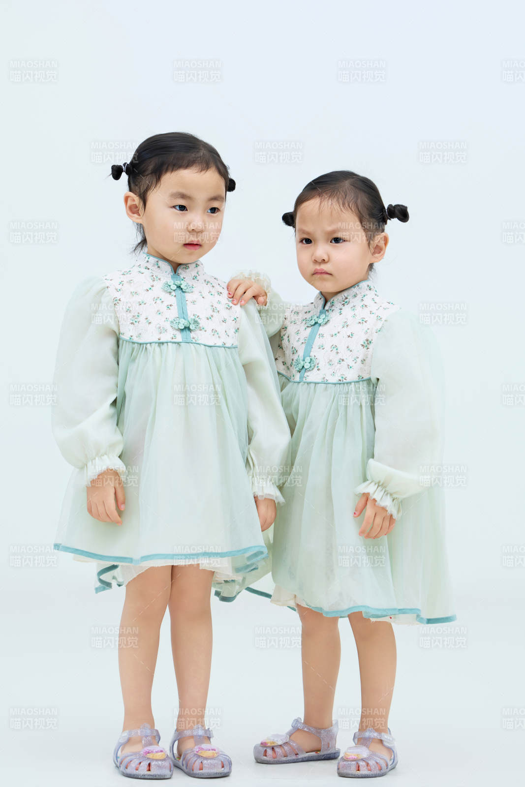 白色背景下顽皮可爱的双胞胎小女孩