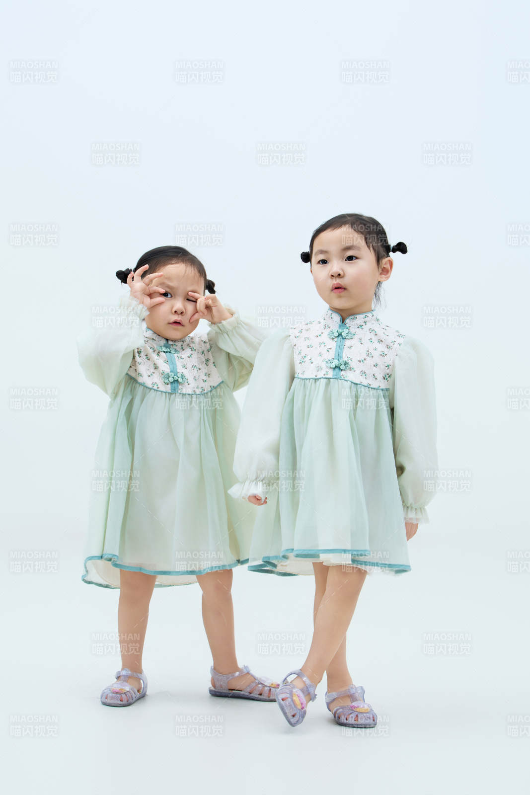 白色背景下顽皮可爱的双胞胎小女孩