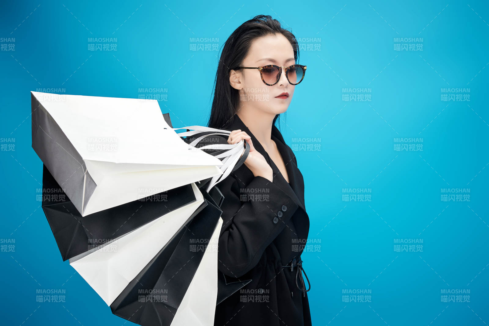 青藍(lán)色背景下手提購(gòu)物袋的亞洲時(shí)尚少女