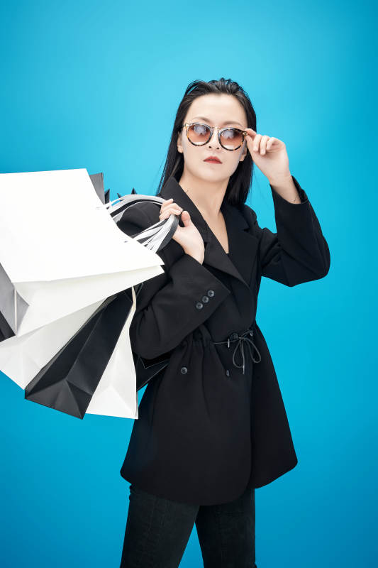 青蓝色背景下手提购物袋的亚洲时尚少女