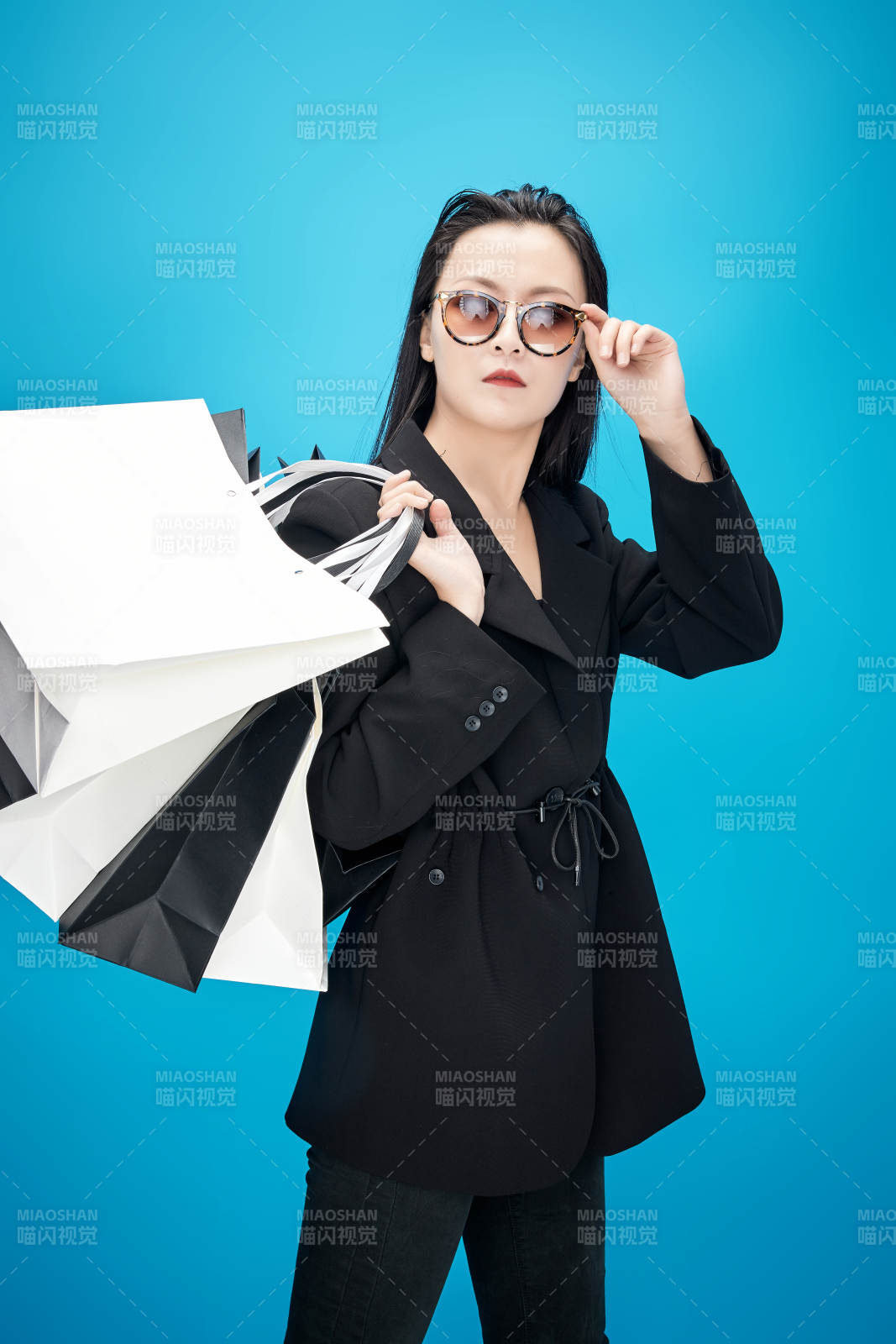 青蓝色背景下手提购物袋的亚洲时尚少女