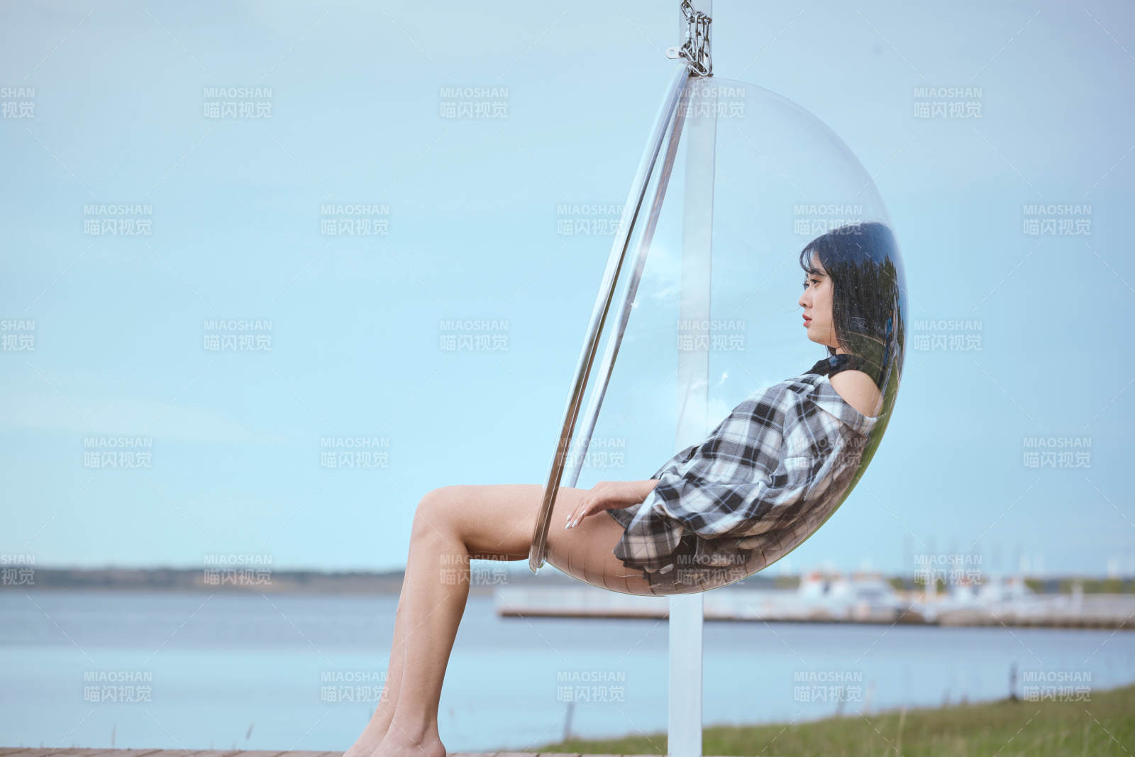 草原湖畔坐在透明秋千里的亞洲年輕女性人像