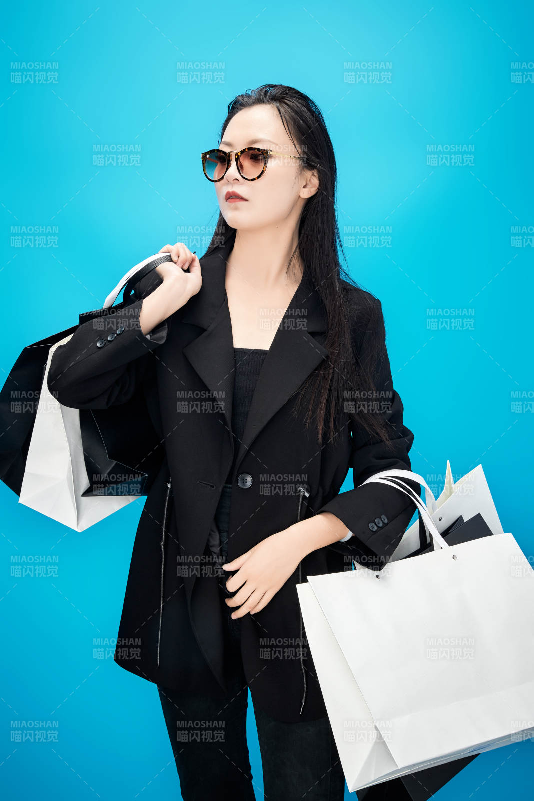 青藍(lán)色背景下手提購物袋的亞洲時(shí)尚少女