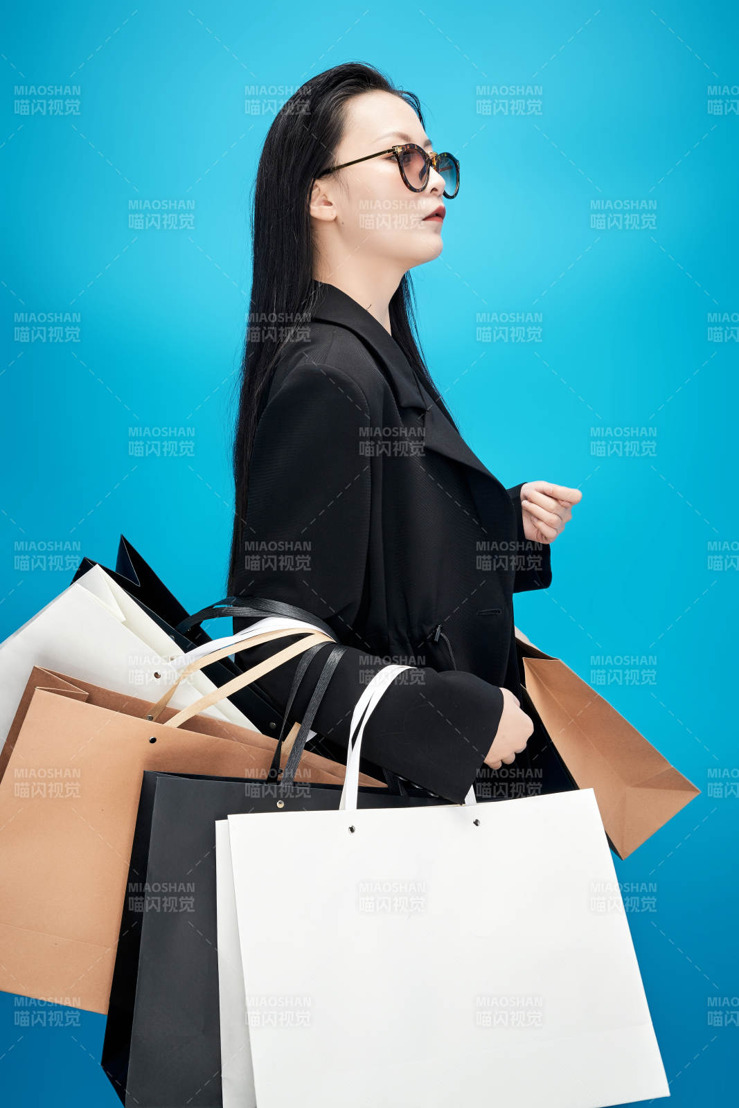 青藍色背景下手提購物袋的亞洲時尚少女