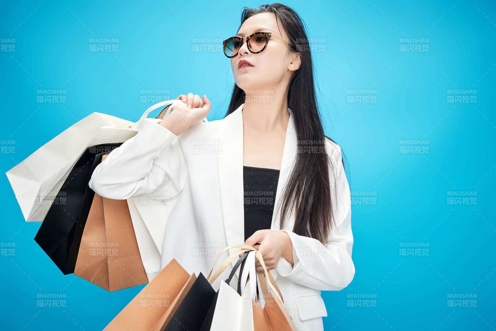 青藍(lán)色背景下手提購物袋的亞洲時(shí)尚少女