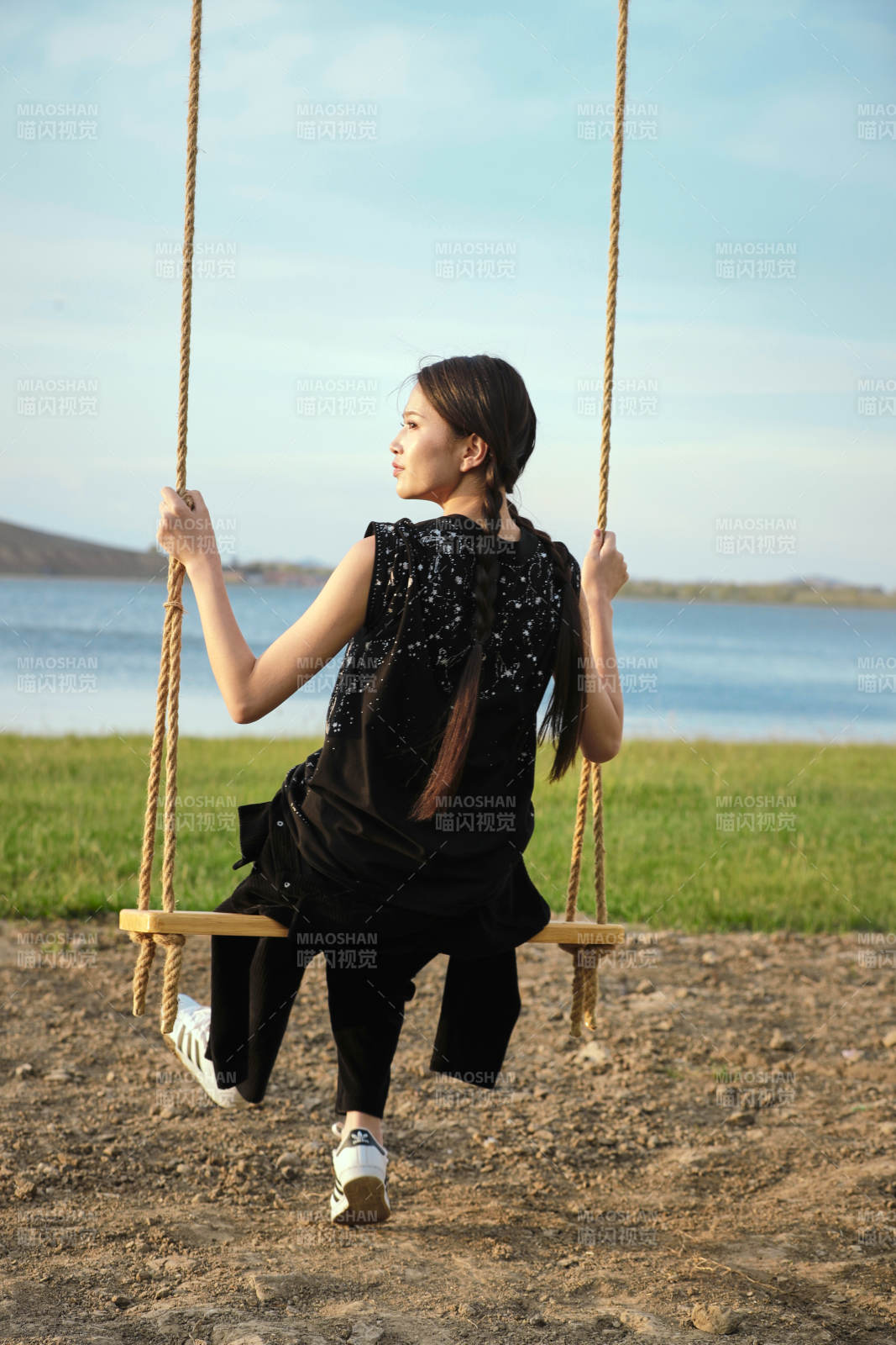 草原湖畔夕阳下荡秋千的亚洲少女