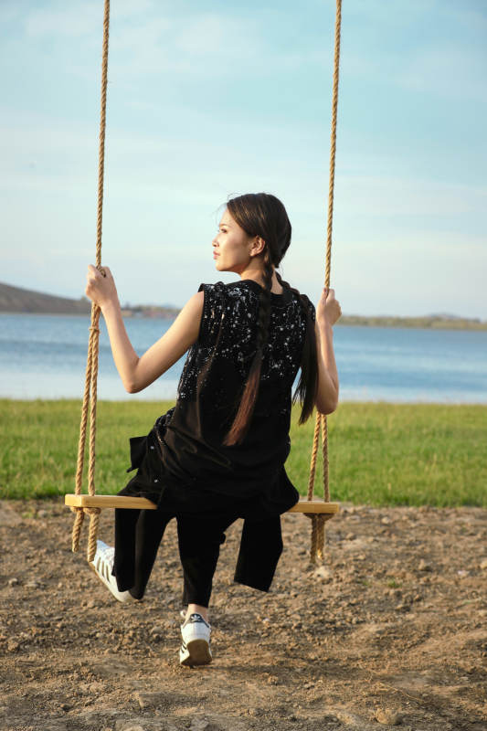 草原湖畔夕阳下荡秋千的亚洲少女