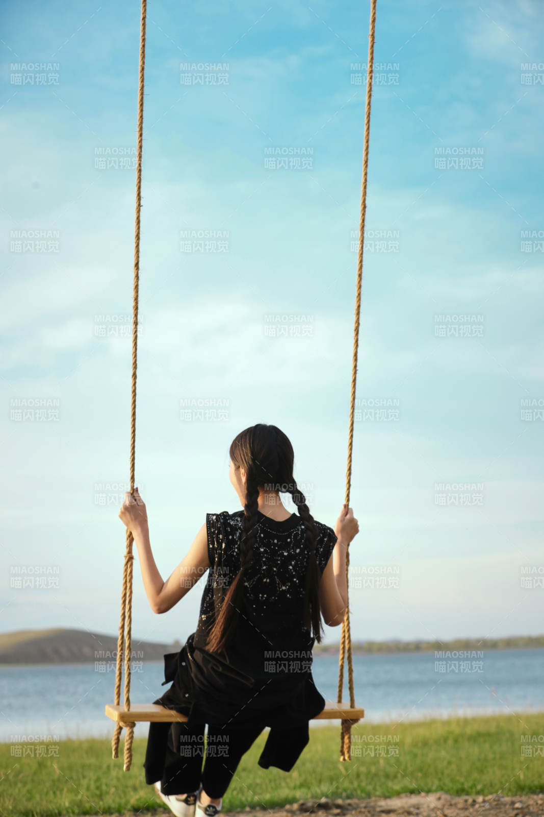 草原湖畔夕陽下蕩秋千的亞洲少女