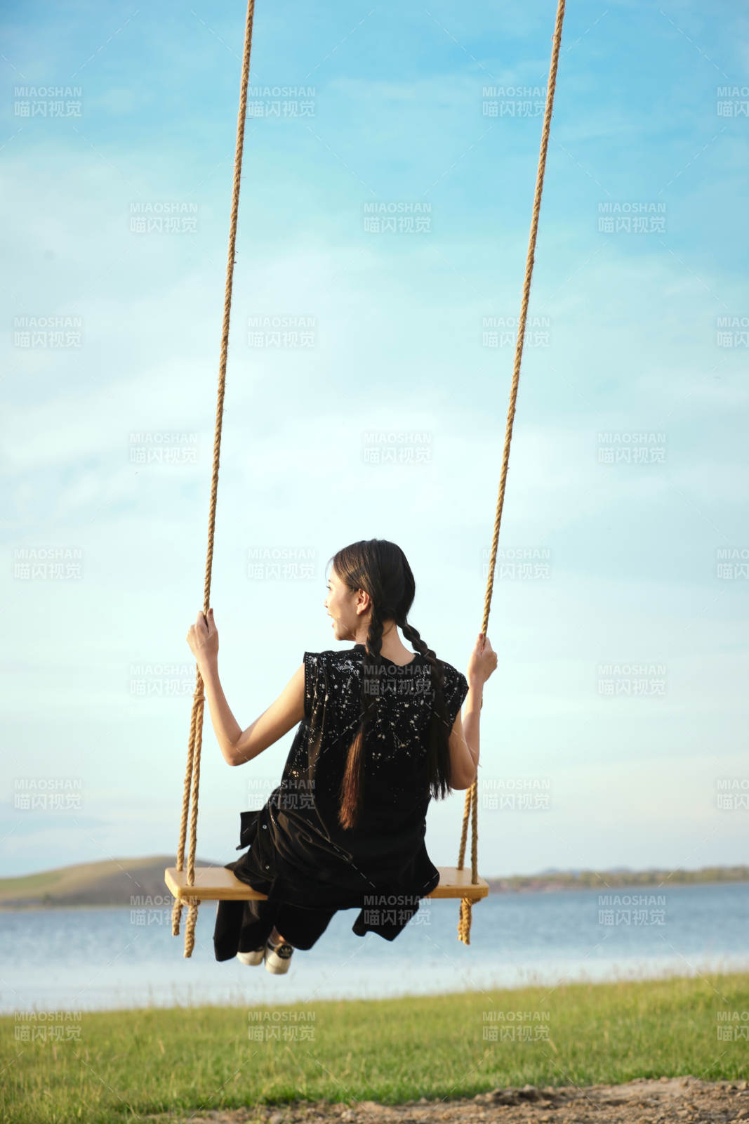 草原湖畔夕陽下蕩秋千的亞洲少女