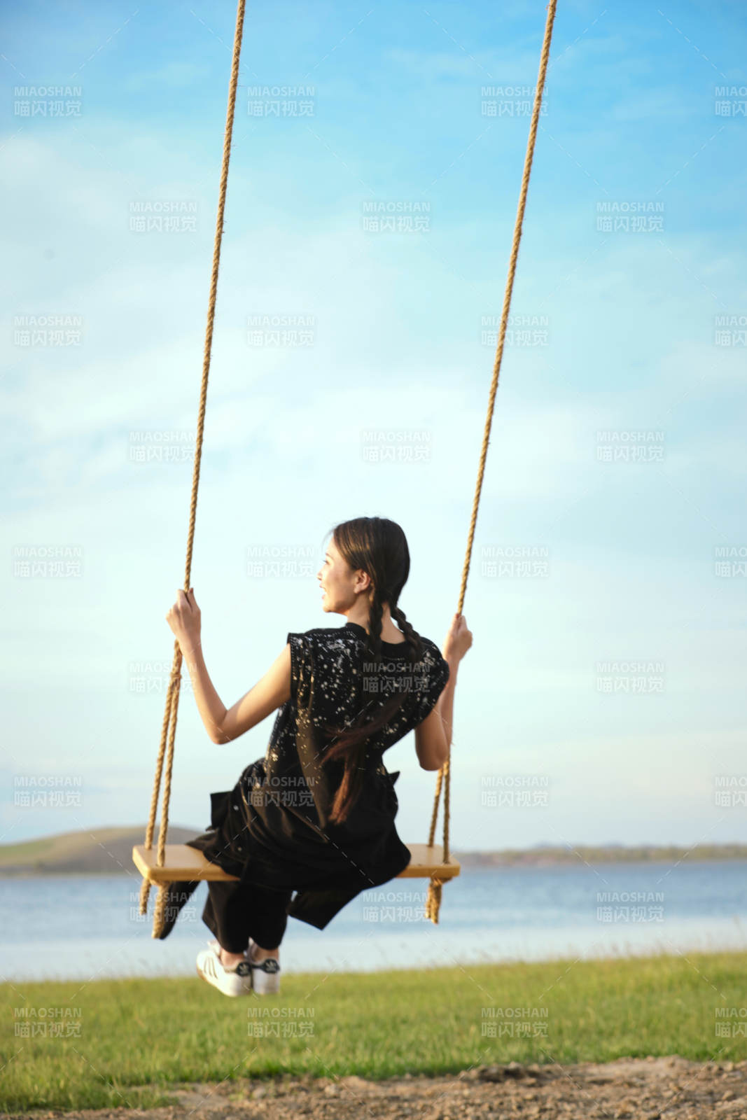 草原湖畔夕陽下蕩秋千的亞洲少女