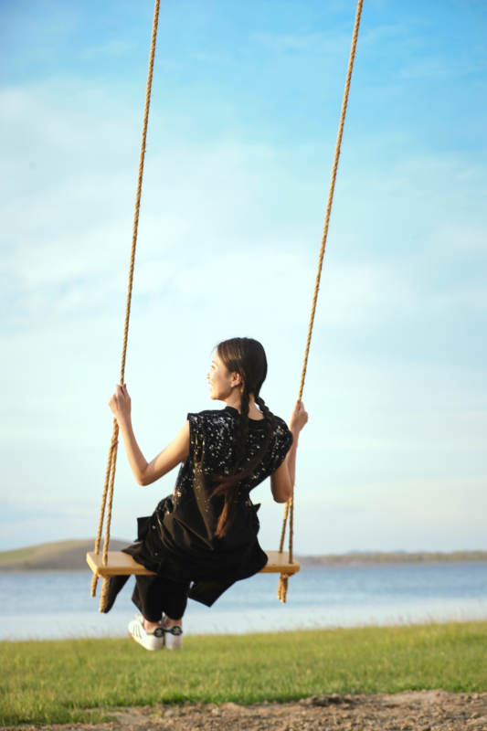 草原湖畔夕阳下荡秋千的亚洲少女