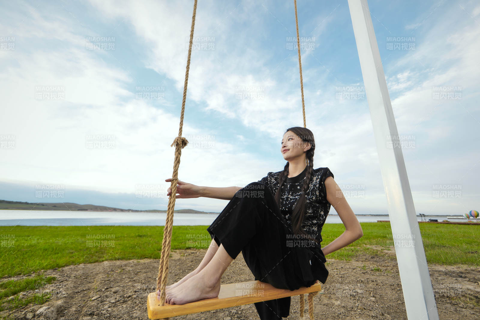 草原湖畔夕陽(yáng)下蕩秋千的亞洲少女