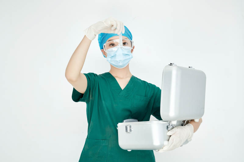 手持外科医疗手术器械箱的年轻女性医生