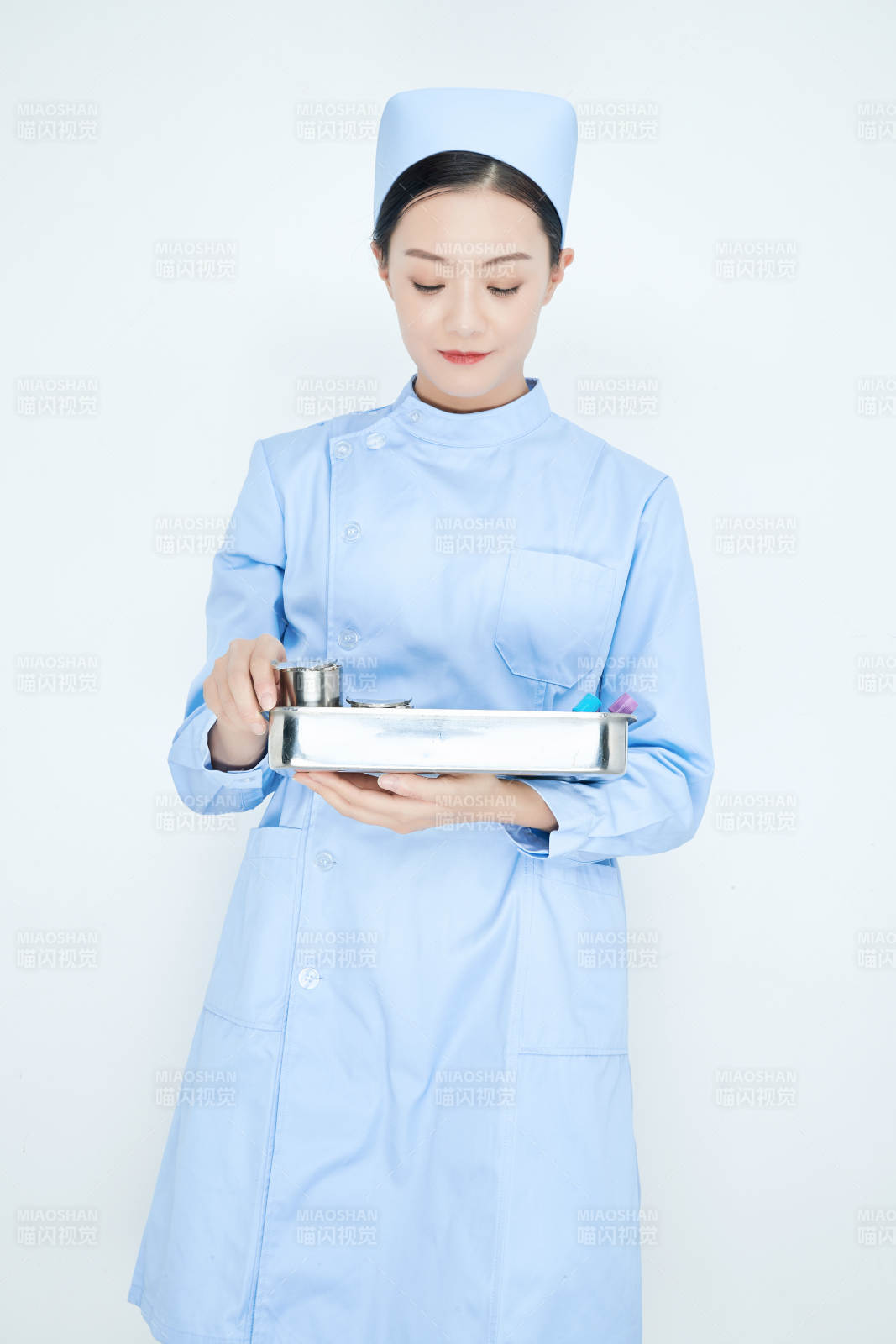 身穿护士服手抱化验托盘的年轻女护士图片