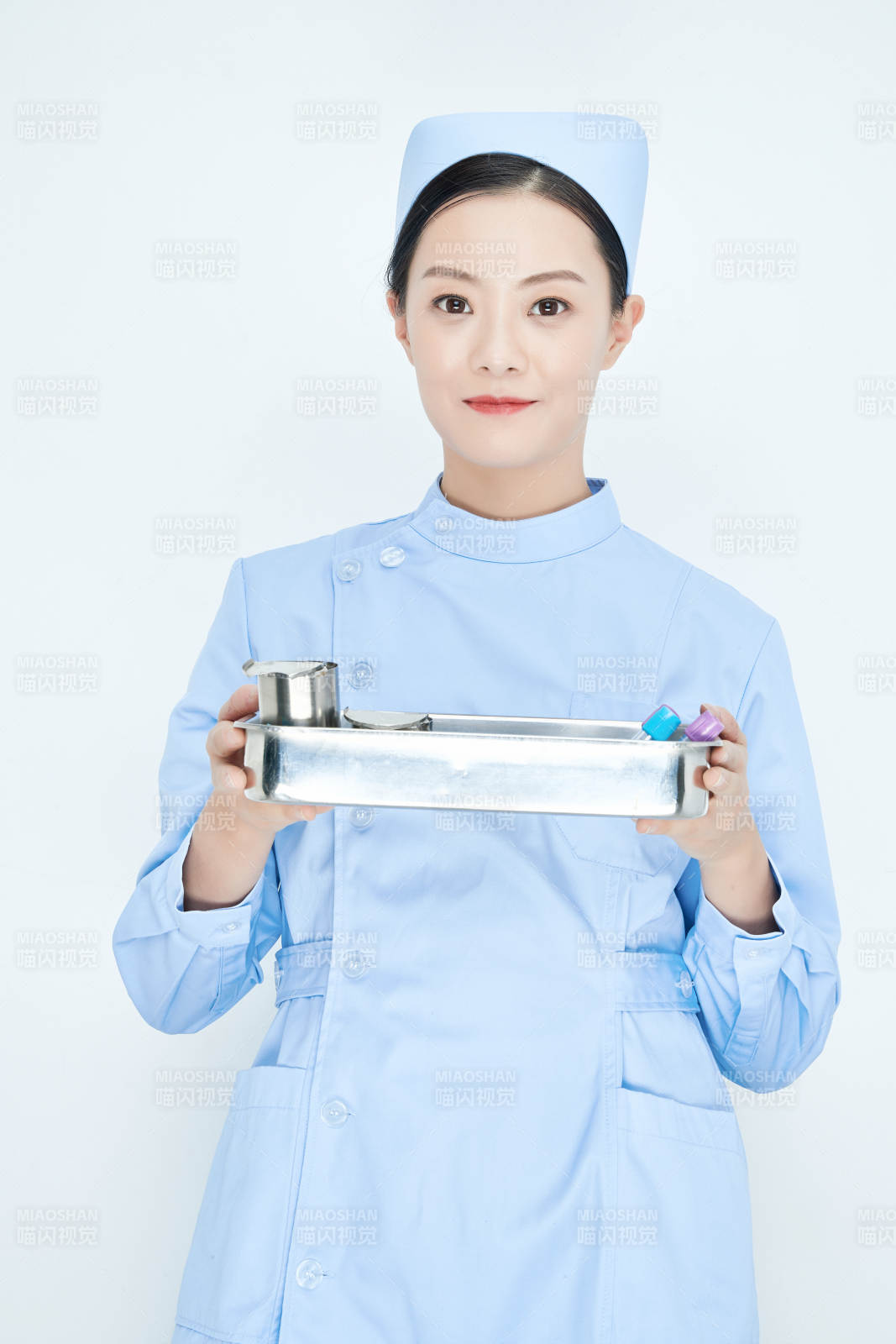 身穿护士服手抱化验托盘的年轻女护士图片