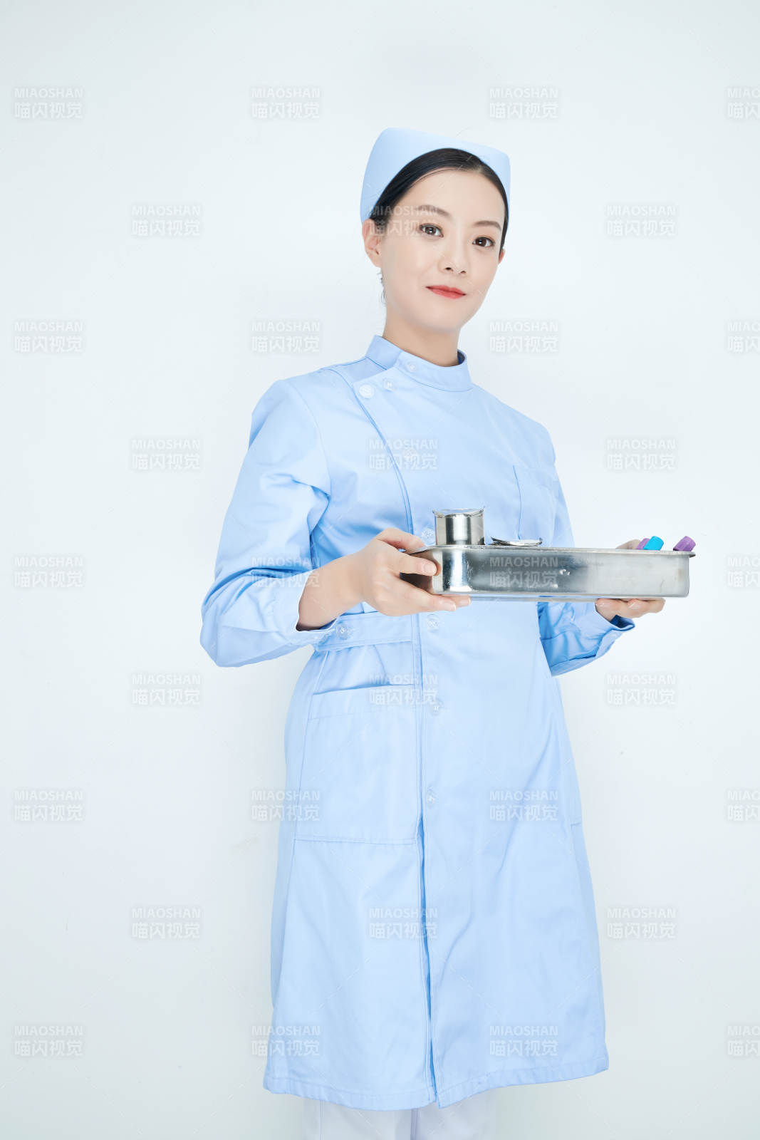 身穿护士服手抱化验托盘的年轻女护士图片
