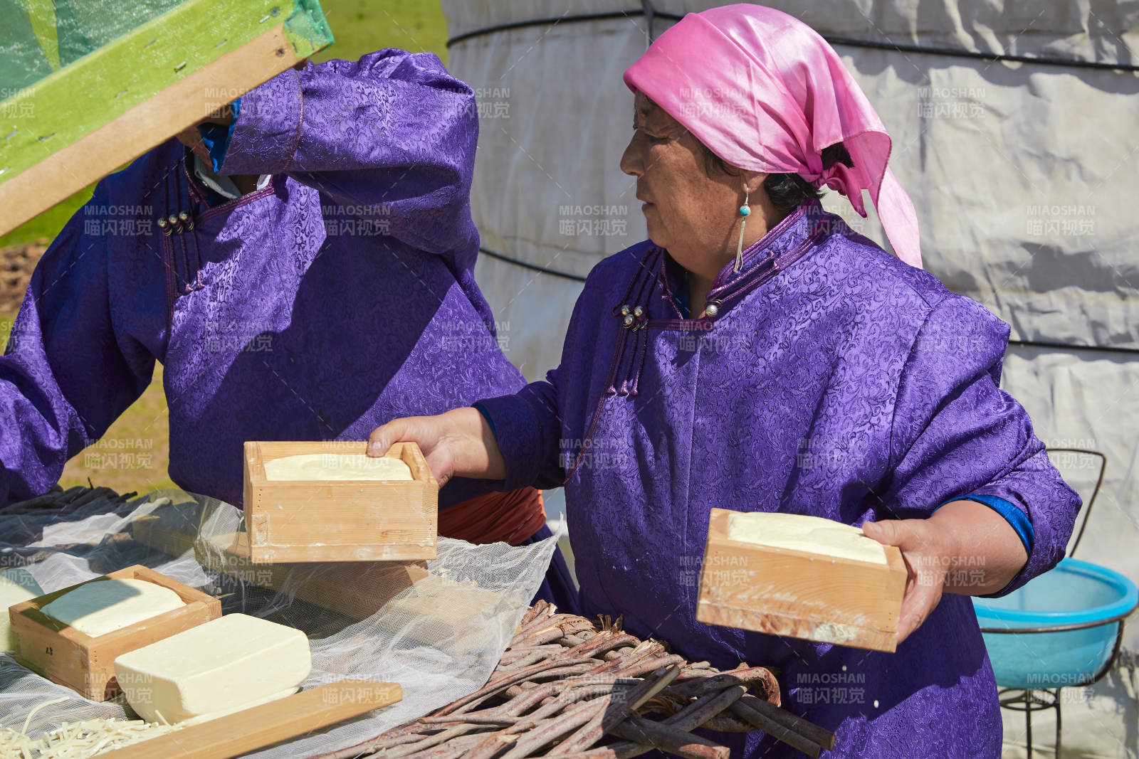 在蒙古包外晾晒奶制品的蒙古族中老年夫妻