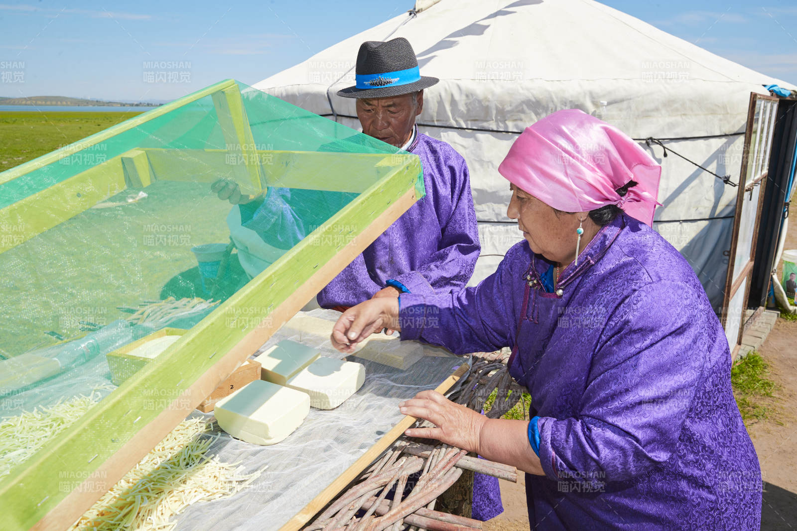 在蒙古包外晾曬奶制品的蒙古族中老年夫妻