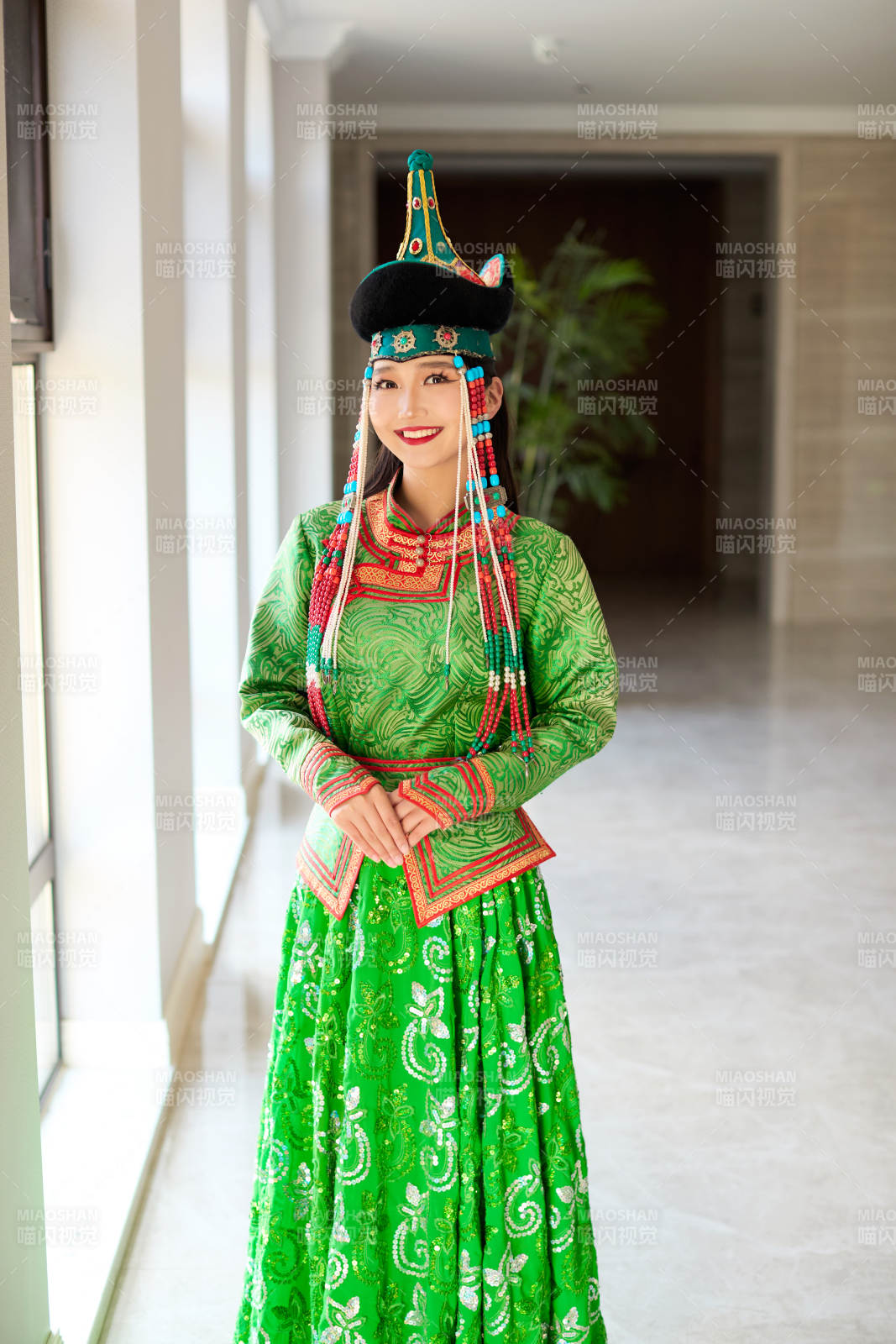 室內穿著綠色蒙古袍的蒙古族年輕女性